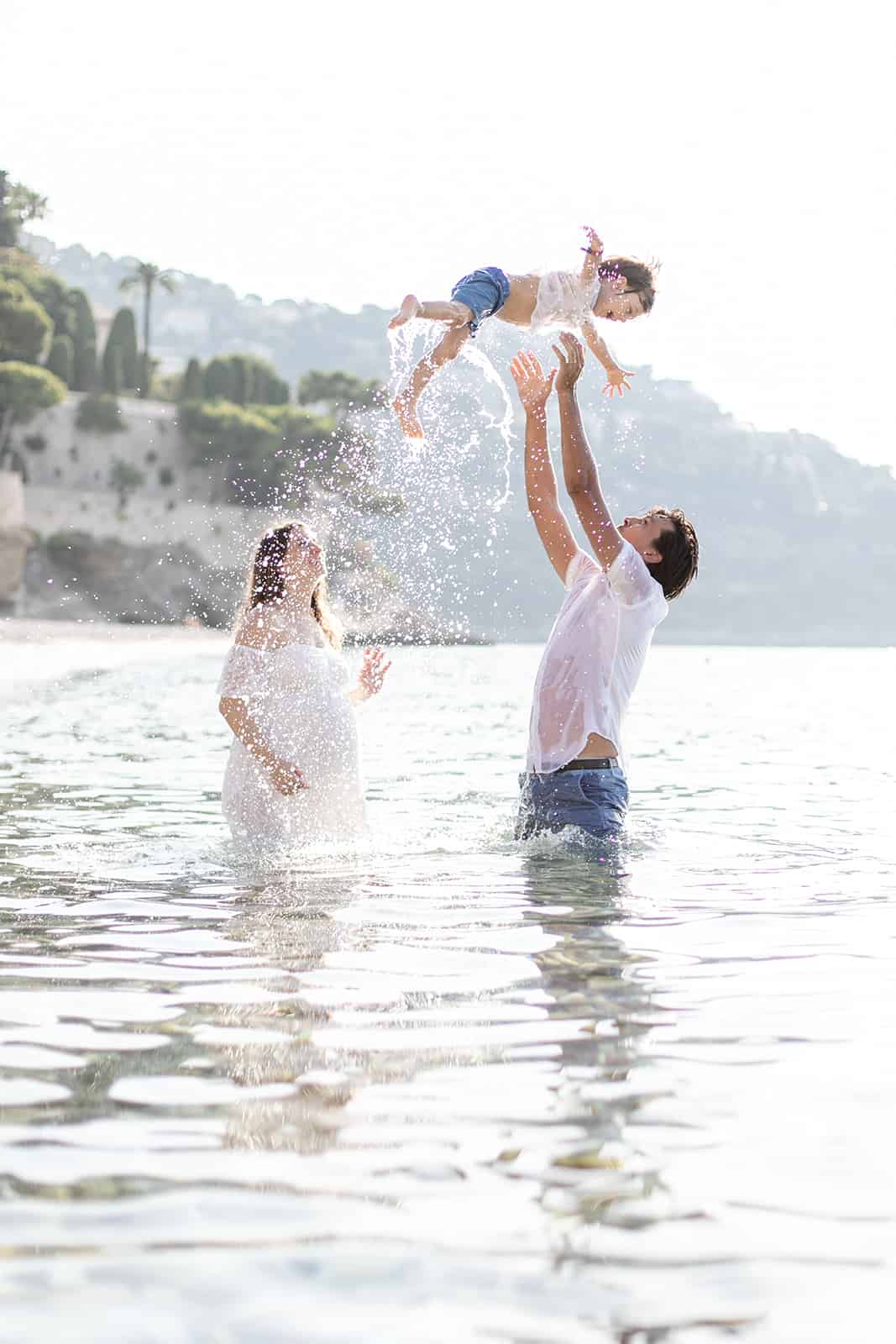 outdoor family maternity session on a beach in Monaco. Dad tossing little boy in the air