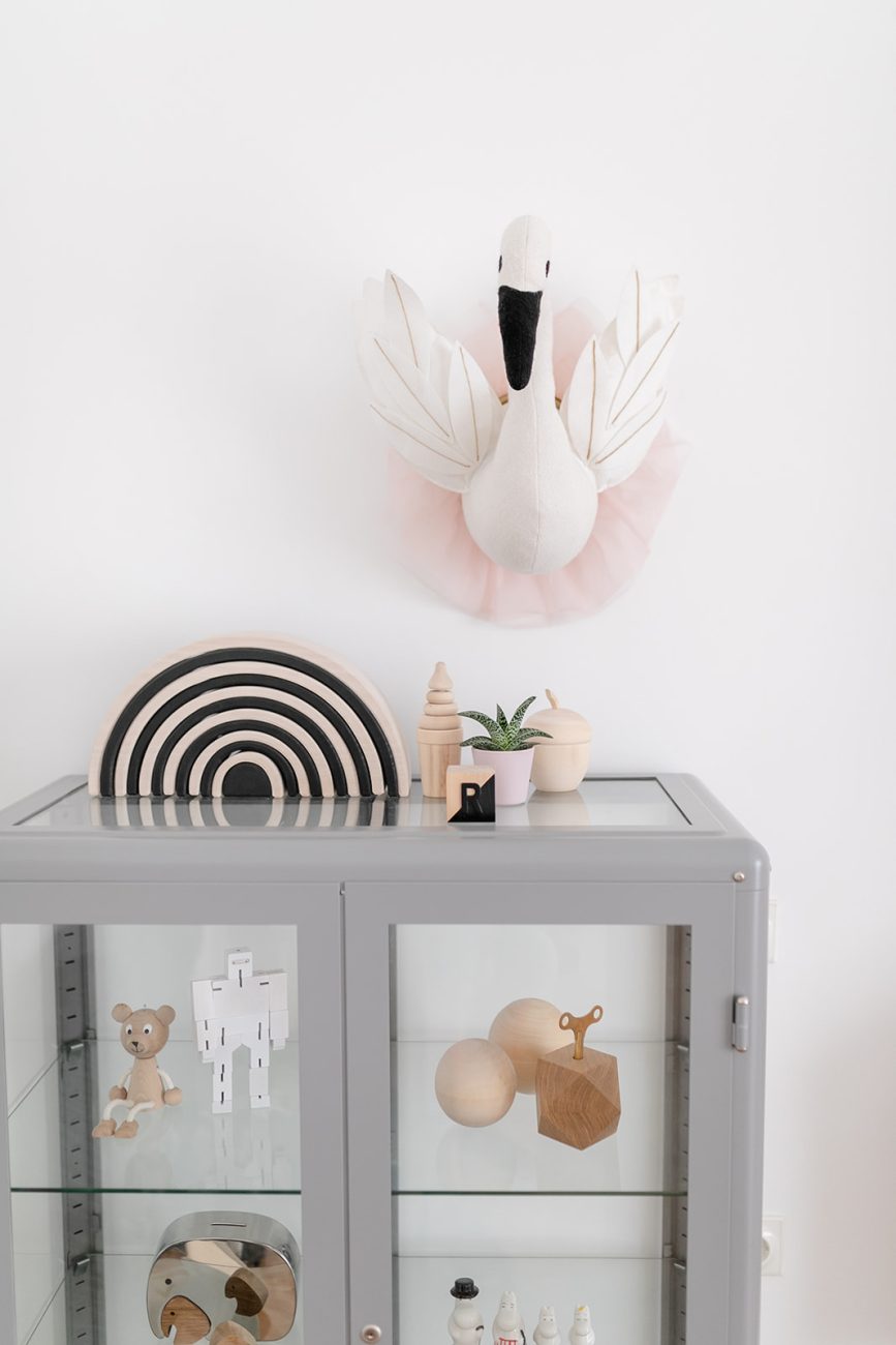 glass cabinet with kids toys, Scandinavian style interior for children, stuffed toy swan head hanging on the wall