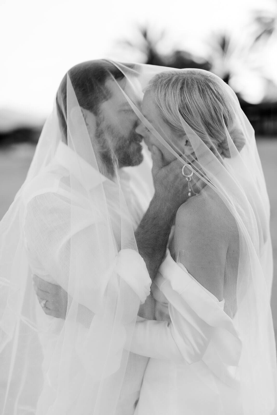 couple kissing under a bridal veil in black and white